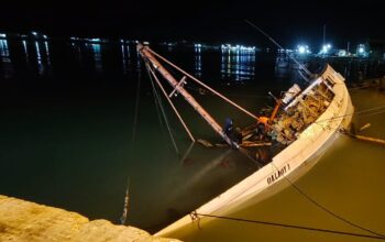 Kapal Pengangkut Batang Kayu Jati Miring di Pelabuhan Kalianget