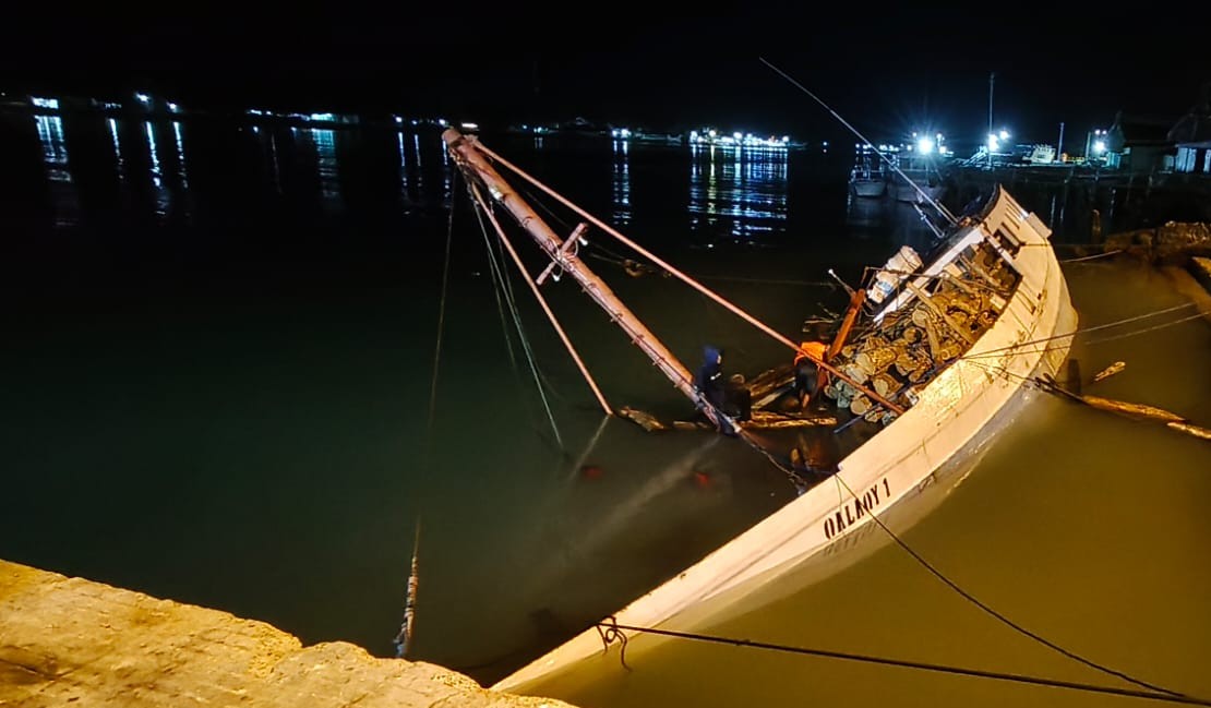 Kapal Pengangkut Batang Kayu Jati Miring di Pelabuhan Kalianget